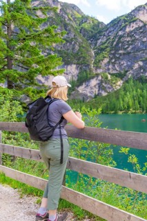Person looking from a wooden fence at a mountain lake, surrounded by nature, Lake Braies, South