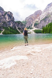 Woman with rucksack looking at the fascinating mountains and the clear lake in front of her, Lake