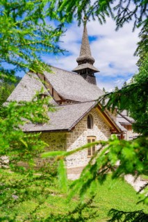 An idyllically situated church with a pointed tower, surrounded by dense vegetation, Lake Braies,