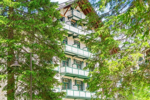 A hotel building with green trees and balconies in a wooded setting, Lake Braies, South Tyrol,