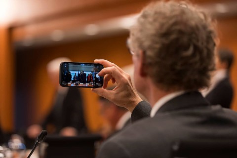 A person takes a photo with their mobile phone in front of the meeting of Federal Chancellor