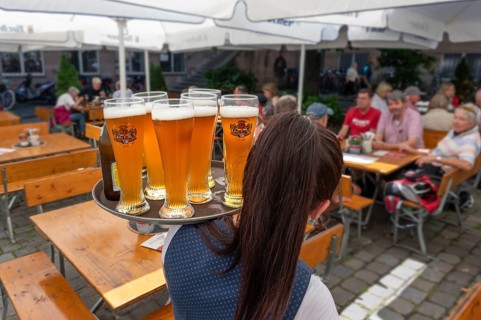 Waitress serving six glasses of wheat beer on a tray to the tables of a garden restaurant, Bavaria,