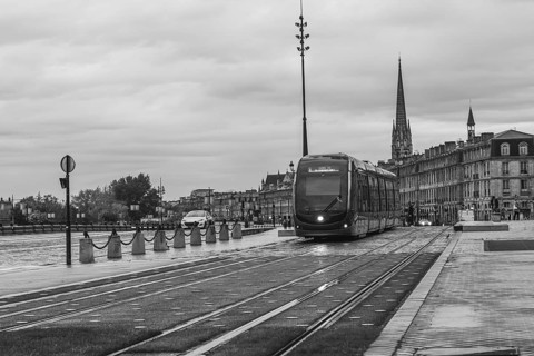 Sleek, modern tram is passing through a bordeaux cityscape, showcasing the city's blend of