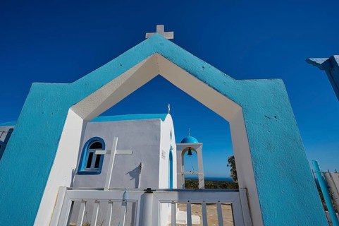 Chapel of Agios Charalambos, Mediterranean church in blue and white under a bright blue sky,