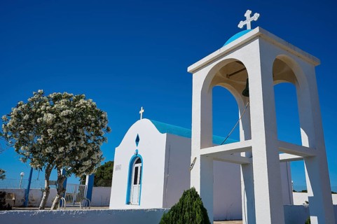 Chapel of Agios Charalambos, White chapel with bell tower and blossoming tree in the background,