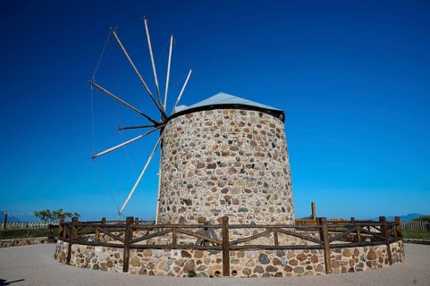 Historic stone windmill with fence and clear sky, Kefalos, Kos, Dodecanese, Greek Islands, Greece