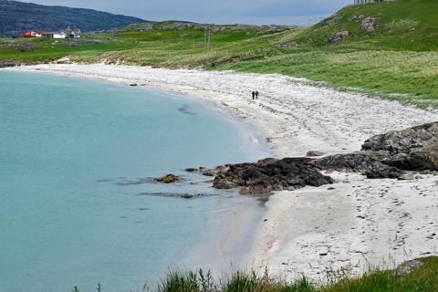 A quiet beach with white sand, green grass and a cloudy sky, Eriksay, Hebrides, Scotland, United