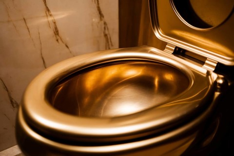 Luxurious glden toilet bowl against marble tiles. Concept for excessive decadent wealth. Generative