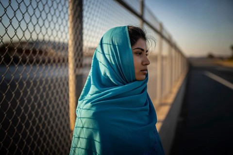 Young female immigrant in turquoise hijab at border crossing. Quiet resilience and contemplation