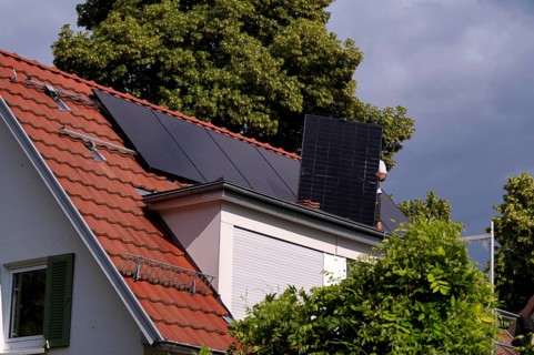 Tradesmen install solar panels, solar modules, solar panels, solar collectors, on house roof,