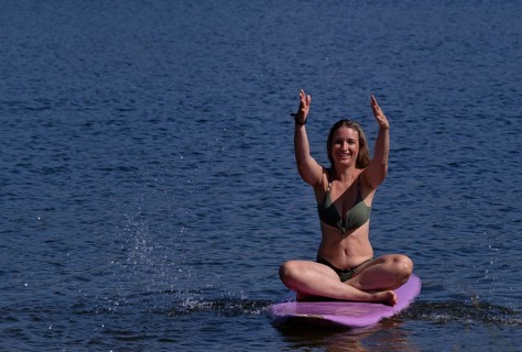 Woman, blonde, in bikini, sitting on board, surfboard, surfboard, purple, back, from behind,