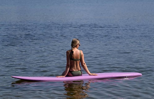 Woman, blonde, in bikini, sitting on board, surfboard, surfboard, purple, back, from behind,