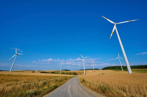 Wind turbines flanking a country road in a quiet wheat field landscape, summer, Wenkheim, Werbach,