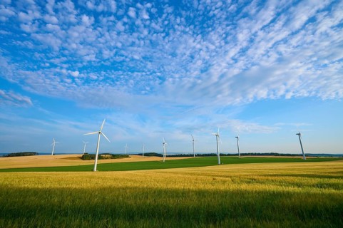 A row of wind turbines on green fields under a cloudy sky, summer, Höhefeld, Wertheim,