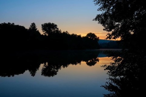 Morning sky over a quiet river Main with trees silhouetted against the orange light, summer,