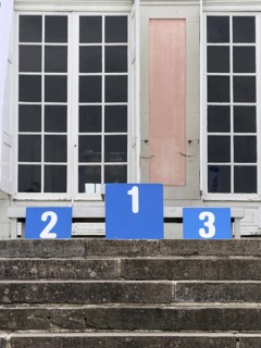 A winner's podium with the numbered places 1, 2 and 3, placed on a stone staircase in front of a