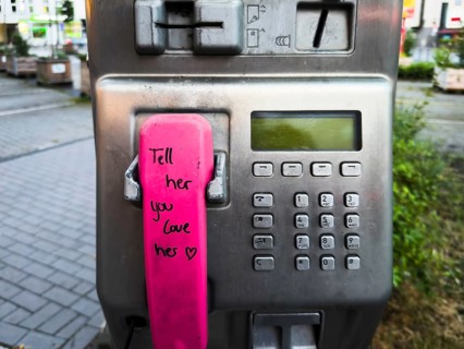 Telephone receiver of a Telekom payphone with the inscription Tell her you love her in Wuppertal,