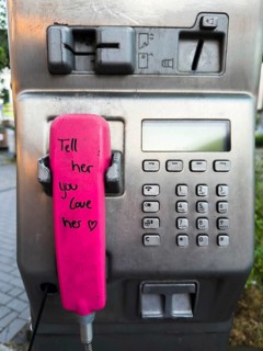 Telephone receiver of a Telekom payphone with the inscription Tell her you love her in Wuppertal,