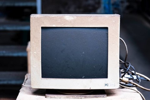An old, dusty CRT monitor (cathode ray tube monitor) with a beige-grey housing. Significant signs