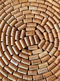 A large number of wine corks laid close together in a spiral pattern. The corks come from different