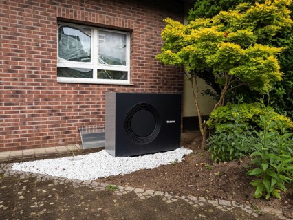 A black heat pump in a front garden in Hilden, Germany
