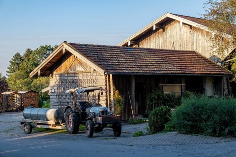 Rural scene with a wooden house and a tractor in the evening light, surrounded by nature, Bavaria,