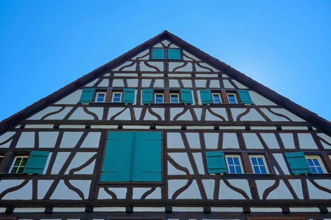 Gable facade of a half-timbered house with green shutters against a blue sky, Triberg im