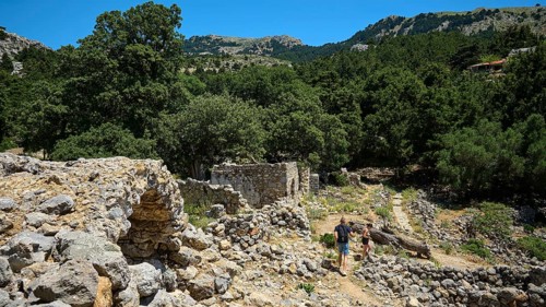 Two people explore ancient ruins surrounded by mountains and forests, Abandoned Village, Lost