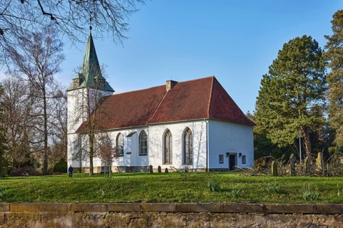 Evangelical Lutheran Church Hille, cemetery, sandstone wall, bare winter trees, blue cloudless sky,