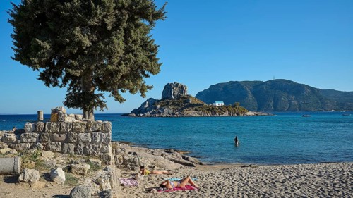 Summer beach view with view of a small island and chapel, Agios Stefanos Beach, Agios Stefanos