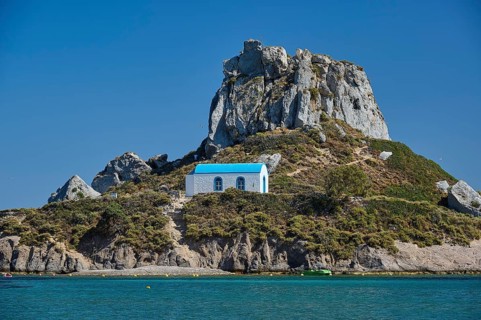 Top of a rocky island with chapel and blue roof, Agios Stefanos Beach, Agios Stefanos Basilica,