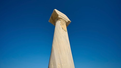 Ancient column imposing against deep blue sky, Agios Stefanos Beach, Agios Stefanos Basilica,