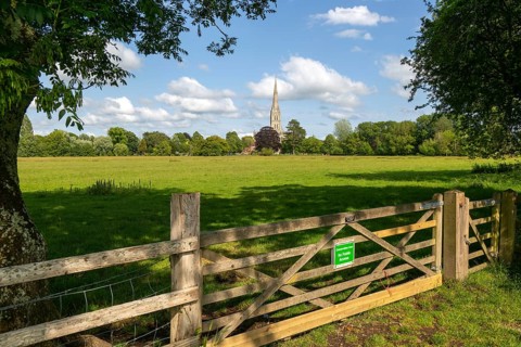 Conservation Area gate view over meadows to Salisbury cathedral church, Salisbury, Wiltshire,