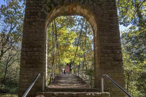 Park visitors walking across the Swinging bridge constructed in 1939 at Tishomingo State Park in