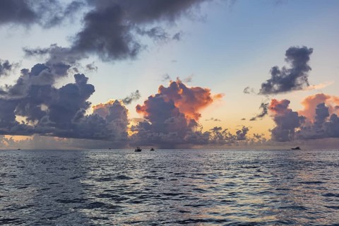 Colorful storm clouds behind the silhouette of offshore fishing boats in the Gulf of Mexico just