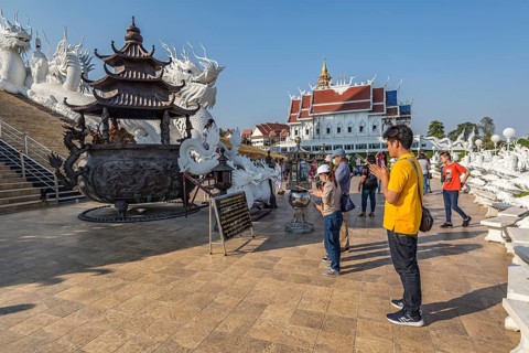 Visitors make a wai phra offering to Buddah in front of the Guan Yin (Goddess of Mercy) statue at