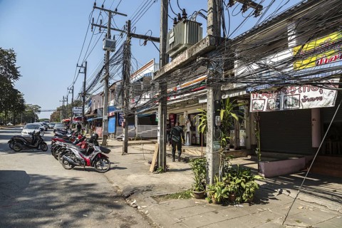 Tangled mess of utility lines above sidewalk along Ban Du street in Chiang Rai, Thailand
