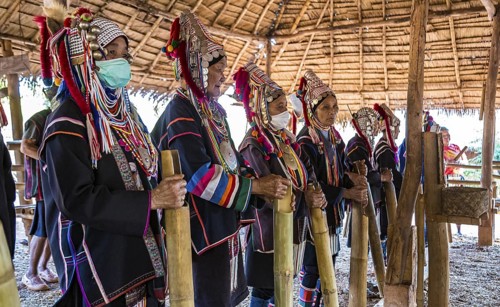 Elderly traditionally dressed people perform a musical chant for a fee in the Akha tribe area of
