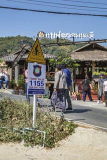 Sign encouraging tourists to call police if needed while visiting Pha Mi Village in Mae Sai