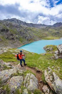 Mountaineers on a hiking trail, view of light blue mountain lake Trüber See in barren mountain