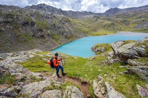 Mountaineers on a hiking trail, view of light blue mountain lake Trüber See in barren mountain