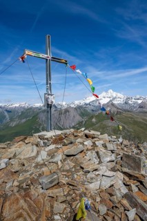 Böses Weibl summit with summit cross and colourful prayer flags, view of picturesque mountain