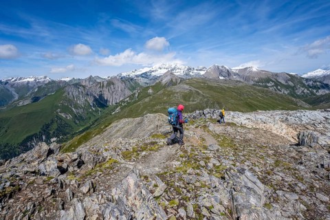 Mountaineers on a hiking trail, view of picturesque mountain landscape with snow-covered summit of
