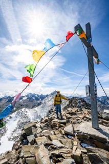 Mountaineers at the summit of Böses Weibl with summit cross and colourful prayer flags, view of