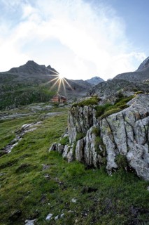 Mountain hut Elberfelderhütte in front of a rocky mountain landscape, sun star in the morning, in