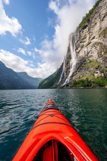Kayak trip on the Geirangerfjord at the waterfall The Seven Sisters, tip of a red kayak in the