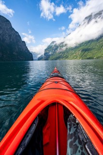 Kayak trip on the Geirangerfjord, tip of a red kayak in the fjord with reflection, atmospheric
