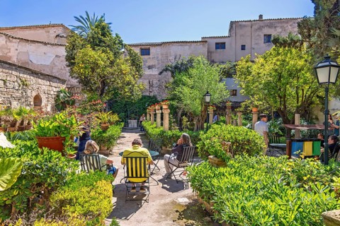 Lush green beautiful garden with visitors at Banys Arabs a historic sites in Palma, Banys Arabs,