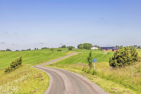 Winding gravel road in the countryside a sunny summer day with passing place road sign, Sweden