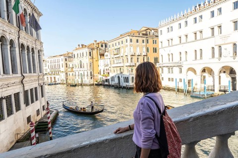 Young woman enjoying view of traditional gondola navigating grand canal amidst historic venetian